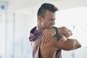man-with-painful-shoulder-holding-it-and-grimacing